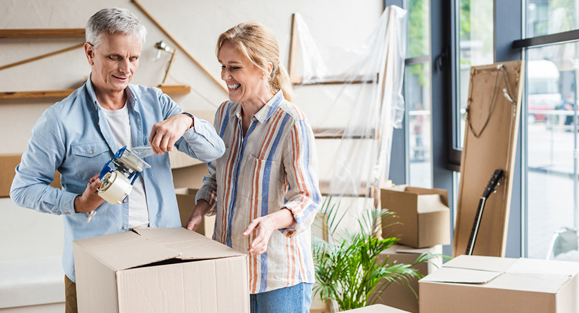 happy senior couple packing cardboard boxes during relocation