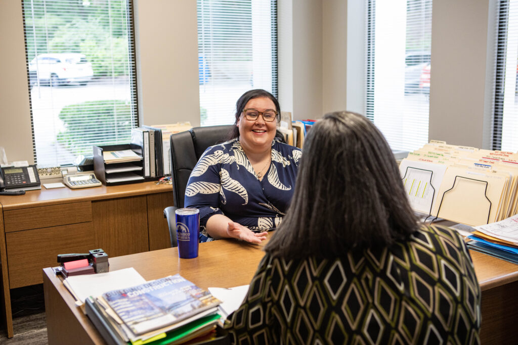 Chrissie Valdini of Rookwood Properties speaking with a client at her desk